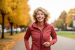 © pham - A woman wearing a red jacket is seen running down a road, showcasing her active lifestyle.