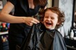 hairdresser fitting a cape on a giggling young child
