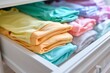 multicolored onesies folded in a nursery drawer