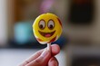 closeup of a hand holding a lollipop with an emoji face on it