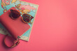 Stylish Travel Accessories with Sunglasses and Red Handbag on a Map Against a Pink Background