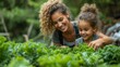 An excited single mother picks fresh vegetables with her daughter from a garden. A cheerful young mother shows her daughter kale from an organic garden. A self-sufficient family gathers fresh produce
