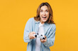 Young gambling excited woman she wears blue shirt white t-shirt casual clothes hold in hand play pc game with joystick console isolated on plain yellow background studio portrait. Lifestyle concept.