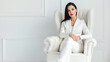 © MYDAYcontent - A woman wearing a white suit is seated on a white chair.
