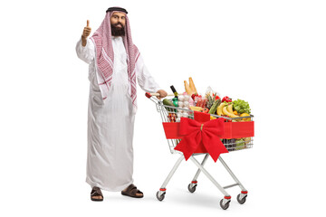 Poster - Arab man standing with a shopping cart full of food products and showing a thumb up sign