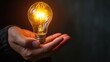 © buraratn - light bulb hold in hand on black background