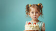 Young Girl with Frosted Cake and Sprinkles on a Teal Background