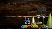 Solemn Background For The Anniversary With The Number 25 . Happy Birthday Background On Brown Wooden Background With Champagne Bottle And Champagne Glasses. Beautiful Holiday Decorations Copy Space.