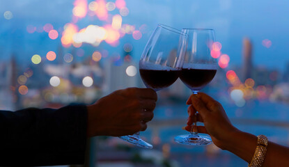 Wall Mural - Hand of romantic couple or friendship which happy moment relaxing ,red,wineglass,celebration on the rooftop in the night with bokeh background