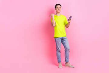 Poster - Full length photo of funky confident man dressed yellow t-shirt texting modern gadget thumb empty space isolated pink color background