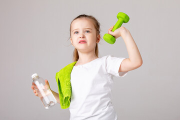 Wall Mural - Little child girl with a dumbbells in her hand on a white background. The child leads a healthy lifestyle and goes in for sports. advertising for a gym or fitness club