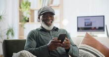 Phone, chat and senior man on sofa with funny meme, gif or social media at home. Smartphone, streaming or old African person in a living room for retirement entertainment with online dating app