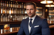 © SOLOTU - A attracrive man in an elegant expensive suit hold a glass of whiskey on blurred bar background. An unrecognizable man holds a glass with an expensive alcoholic drink. Generative Ai