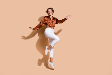 Sticker - Full length photo of carefree shiny woman wear brown blouse jumping high empty space isolated beige color background