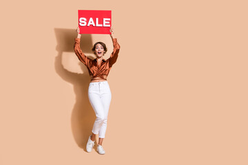 Poster - Full length photo of impressed funky woman wear brown blouse rising sale billboard empty space isolated beige color background