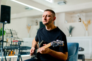 rock performer with electric guitar in recording studio playing musical instrument during rehearsal