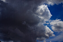 Drastic Change In Weather, With Large Black Cumulus Cloud Covering The Blue Sky.