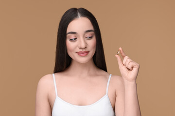 Wall Mural - Beautiful young woman with vitamin pill on beige background