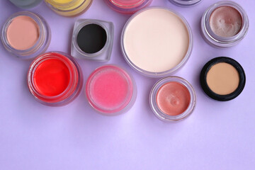 Wall Mural - Bowls with various colorful cream beauty products on purple background. Top view.