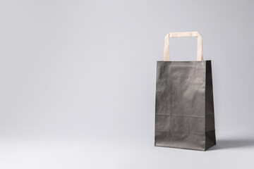 Wall Mural - Black paper bag on light grey background, space for text