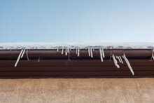 Icicles On The Edge Of The Roof Against The Blue Sky