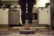 Woman standing on a weight scale in her kitchen