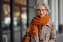 A Stylish Woman, With A Bright Orange Scarf And Cozy Sweater, Smiles Confidently While Sporting Fashionable Glasses And A Chic Shawl, Standing On A Bustling City Street Surrounded By Buildings And Sh