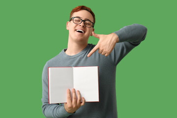 Wall Mural - Young man pointing at blank open book on green background