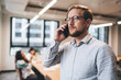 © BullRun - Serious businessman in eyeglasses talking on smartphone