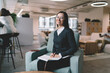 © BullRun - Cheerful businesswoman with notepad sitting on armchair