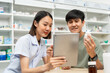 © Chanakon - Pharmacist recommends medicines to customers.Taking the questions of medication. Asian female pharmacist giving prescription medications to customers at drugstore shelves.