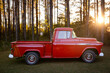 An old retro classic red American pickup truck parked outside in the country