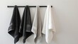 White, black, and grey cotton terry towels hanging on a rail, isolated