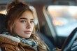 © Pinklife - A young woman with brown hair sits in her car, her human face a portrait of determination as she gazes confidently out into the outdoor world ahead