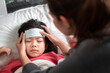 Asian mother take cool gel for reduce high fever on sick girl forehead on bed at morning time,  Selective focus, Healthy and infection concept