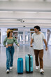 © EDER - vertical portrait multicultural couple walking through the airport terminal with their luggage