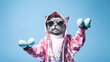 A quirky cat dressed in a pink bunny hoodie, complete with ear flaps, holds two speckled blue Easter eggs. Behind sunglasses, it strikes a playful, festive pose against a blue backdrop