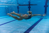 Fototapeta Tęcza - Underwater photo, girl swimming in a sports pool, side view.