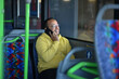 a lustful dark-skinned young man is sitting in the bus and talking on the phone