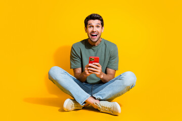Aufkleber - Full length photo of positive impressed guy wear khaki t-shirt communicating modern gadget isolated yellow color background