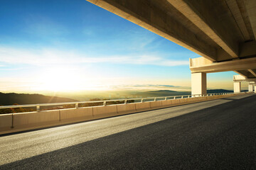 Wall Mural - Modern highway road under the overpass with sunset sky.