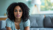 © Jammer Gene - Concerned black woman sitting on a sofa at home.