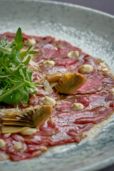 Wall Mural - Italian carpaccio with artichokes, arugula in a plate. A delicious snack