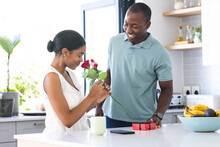Young African American Man Surprises Biracial Woman With A Rose At Home