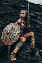 Poster - AI generated illustration of a female warrior in armor and shield standing on rugged rocks