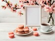 Blank greeting card or wedding invitation with pink cherry blossoming with coffee cup and macarons over white wooden table. mothers day background