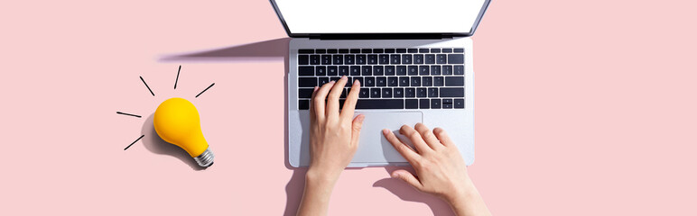 Poster - Person using a laptop computer and a light bulb - Flat lay