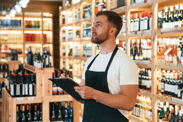 Wall Mural - Quality control, with notepad. Wine shop owner in white shirt and black apron