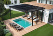 Modern black bio climatic pergola with top view on an outdoor patio. Teak wood flooring, a pool, and lounge chairs. green grass and trees in a garden. 