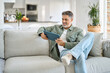 © insta_photos - Happy middle aged man using digital tablet relaxing on couch at home. Happy mature male user holding tab computer browsing internet on pad technology device sitting on sofa in living room.